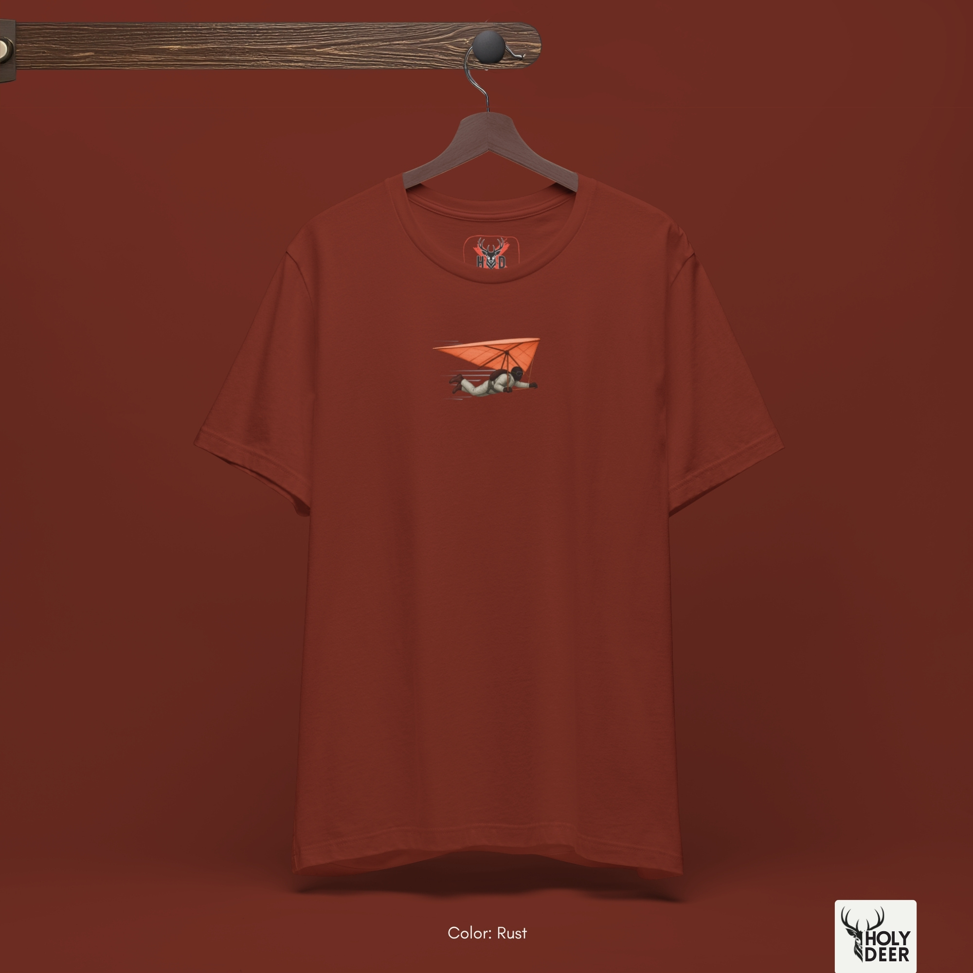 Professional flat lay photography of the Hang Glider Tee by Holydeer Apparel, arranged cleanly next to retro leather flight goggles, mechanical altimeters, and premium aviation sport accessories.