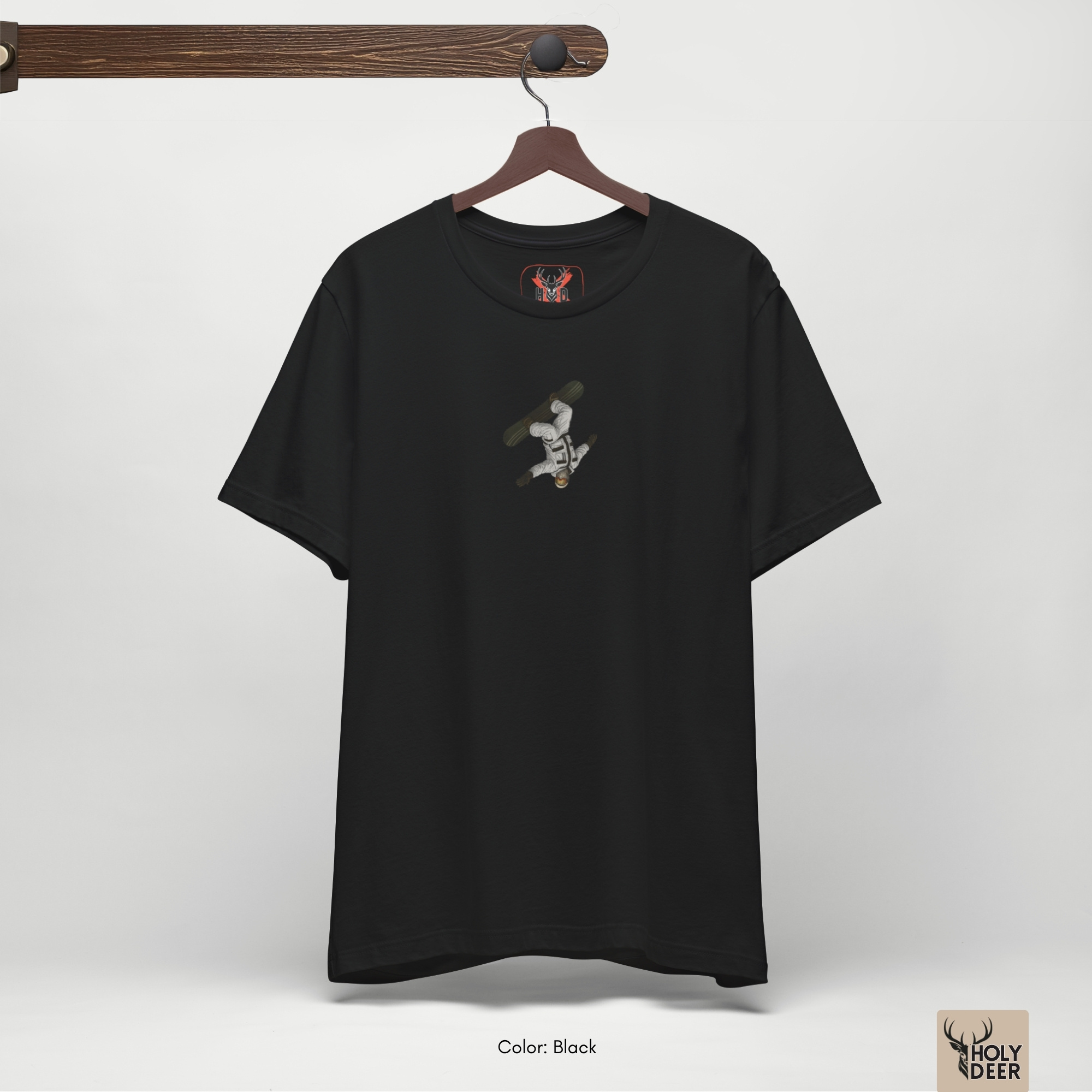 Professional flat lay photography of the Backflip Snowboard tee by Holydeer Apparel, arranged cleanly next to technical snowboard bindings, zero-frame mountain goggles, and premium mountain life wear items.