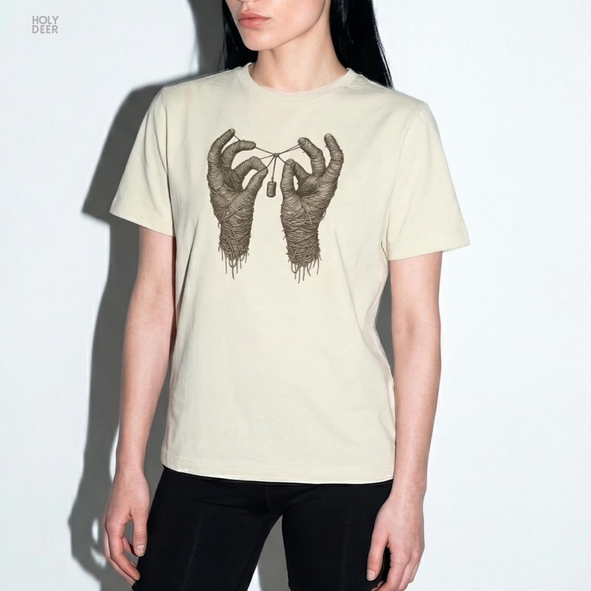 Soft sepia dust ray shadow studio backdrop framing the unique Mummy Hands Shirt by Holydeer Streetwear, magnifying the clean centered spooky mummy art placement and premium surreal mummy top presentation.