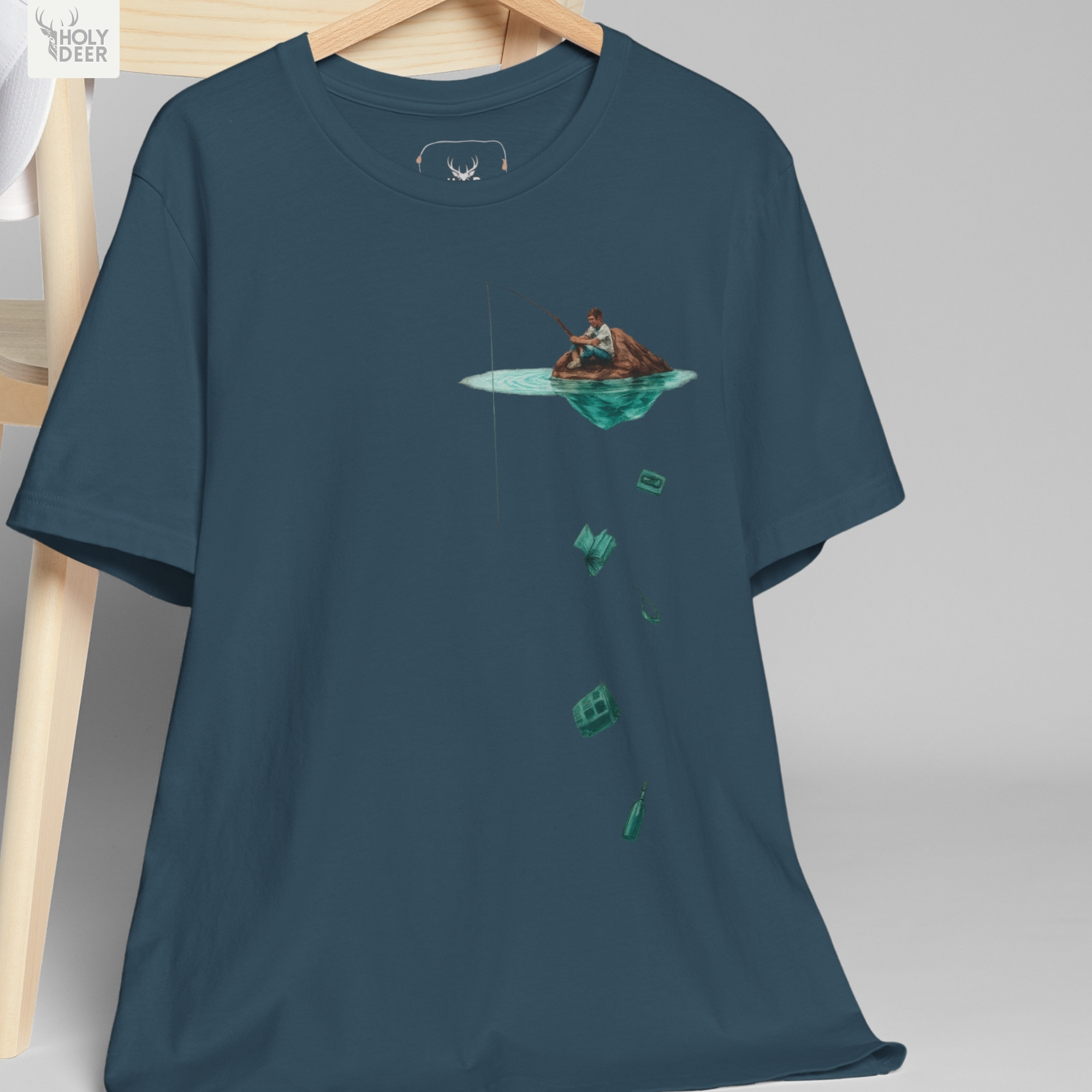 Macro view of the Surreal Fishing Tee print showcasing intricate ink shading on the miniature fisherman sitting on a rock mound, the clean neon turquoise surface ripple, and fine line accents crafted exclusively by Holydeer Streetwear.