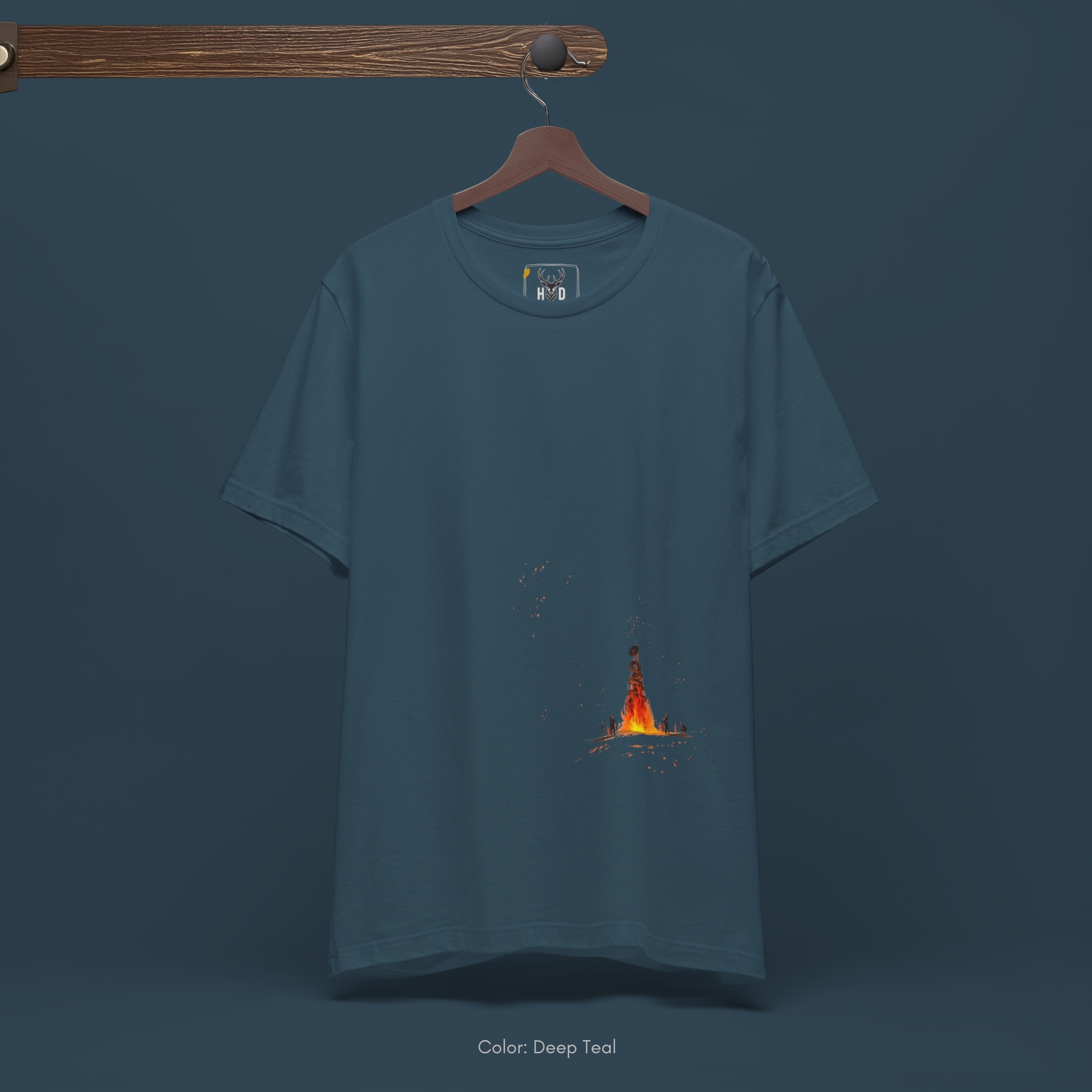 Overhead lookbook arrangement displaying the campfire tee folded neatly alongside blackened forest timber pieces and fiery orange carnelian stones.