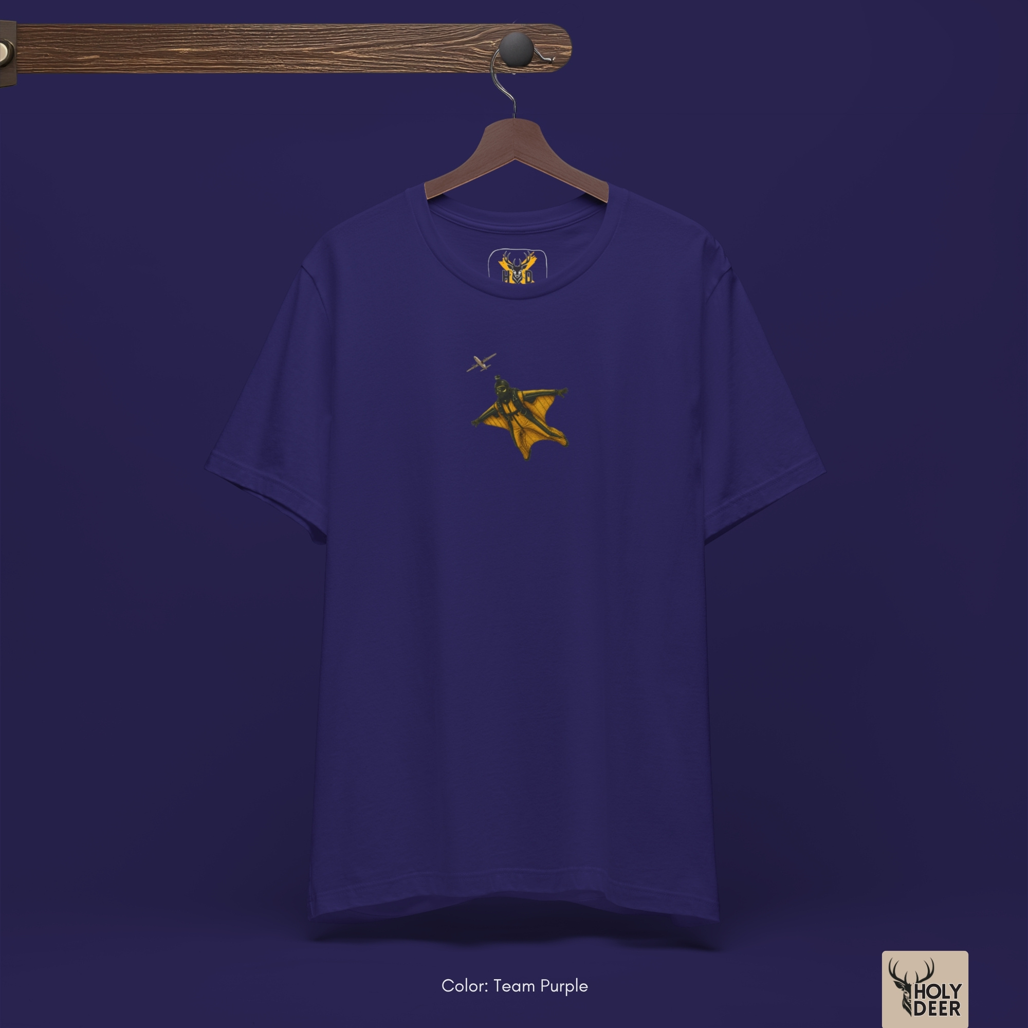 The iconic Wingsuit Pilot Tee hanging cleanly on a luxury wood hanger, highlighting the robust neckline structure, vertical pro wingsuit art flow, and the official holydeer.com retail tags.