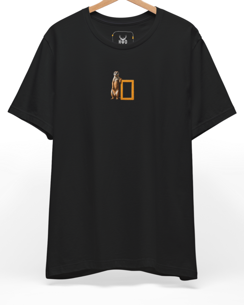 A high-end display of the official Holydeer Meerkat Graphic Tee showcasing unique Safari Aesthetic design lines. The central Cool Animal T-Shirt graphic features a miniature Geographic Parody layout centering a detailed Minimalist Meerkat leaning on a bright National Geographic Shirt style yellow frame printed squarely on a black shirt canvas.