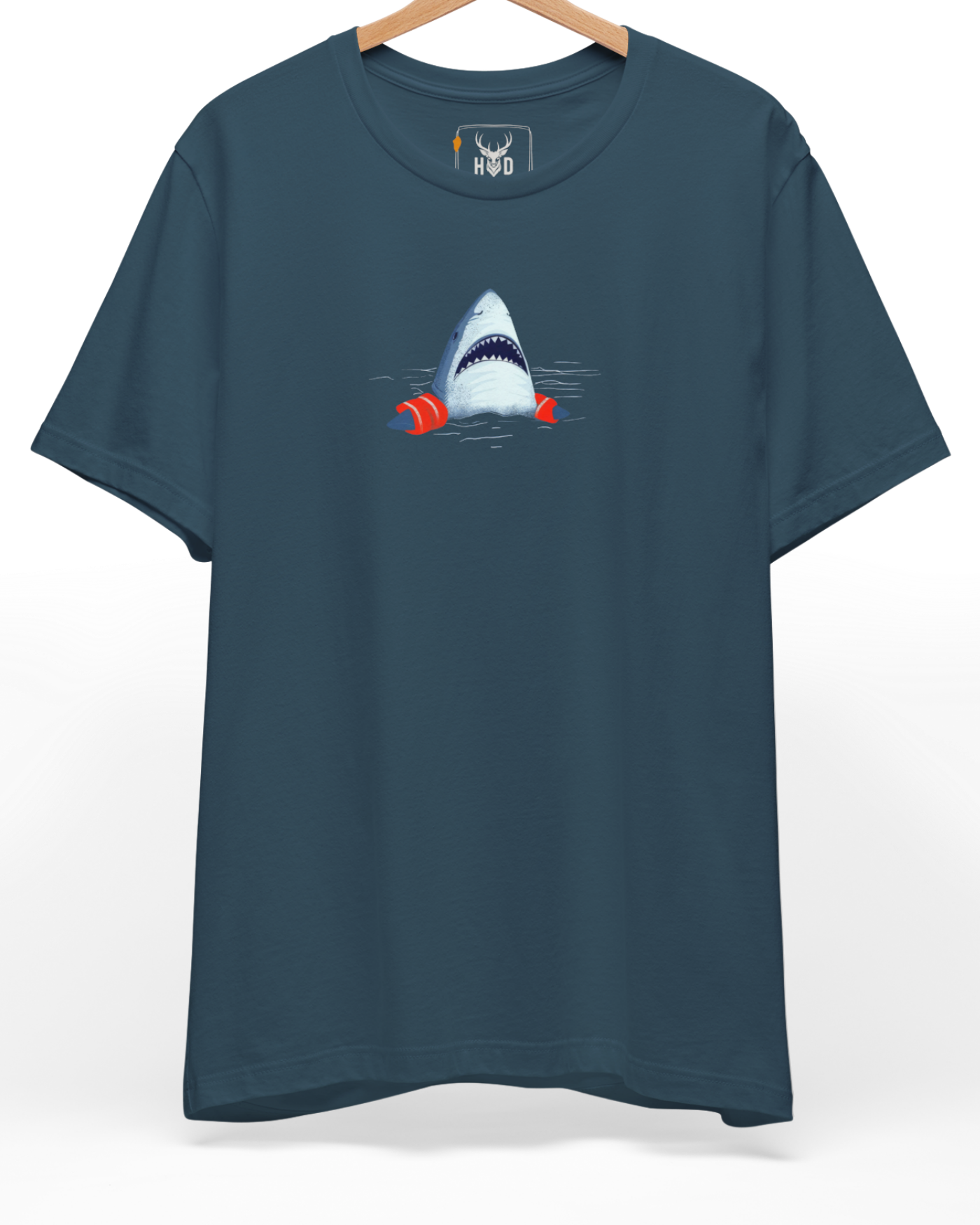 A high-end display of the official Holydeer Shark Graphic Tee showcasing unique Ocean Humor Apparel design lines. The central Cute Shark Clothing graphic features a miniature Nautical Streetwear layout centering a detailed shark head with sharp teeth wearing bright orange Shark Floaties Tee arm bands printed squarely on premium deep teal fabric.