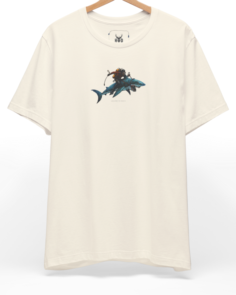 A high-end display of the official Holydeer Shark Graphic Tee showcasing unique Nautical Streetwear design lines. The central Underwater Rodeo graphic features a miniature Surreal Shark Art layout centering a detailed Diver Gift Shirt shark with a custom yellow-tank scuba diver gift riding on its back printed squarely on a natural canvas.