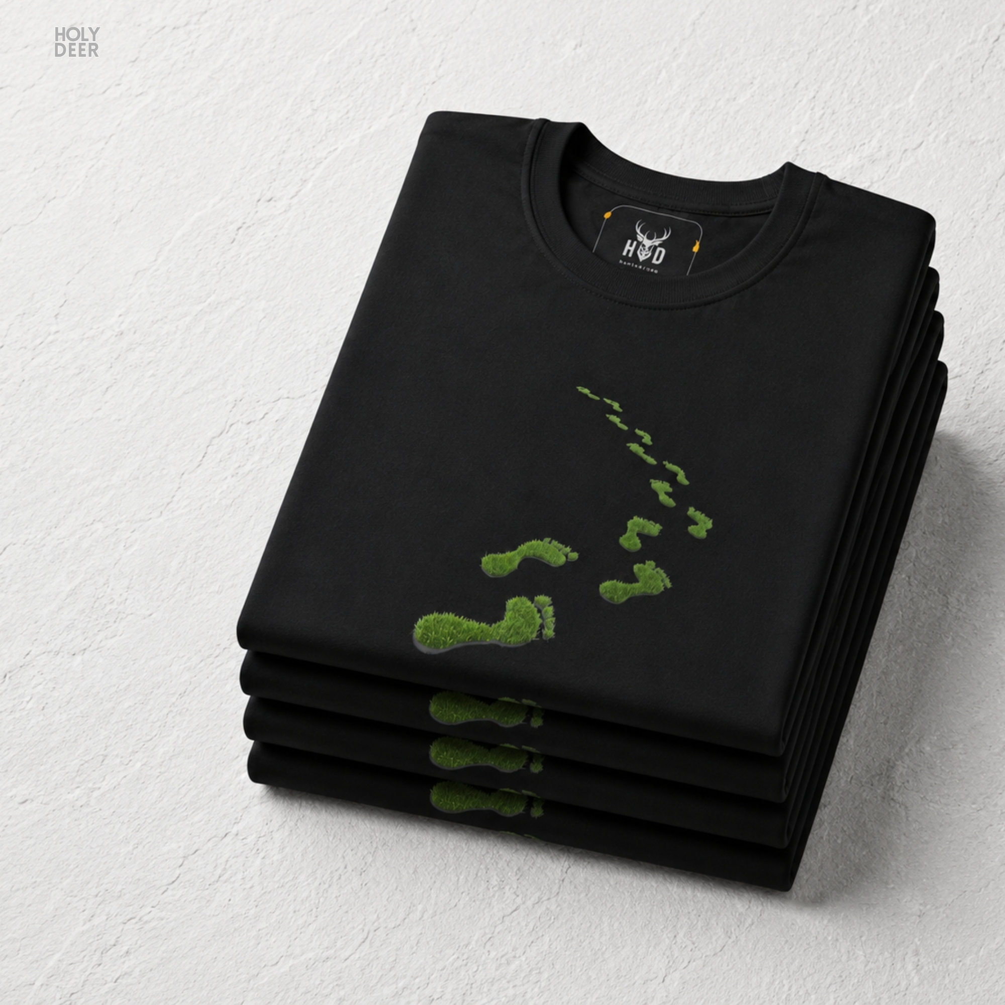 A detailed macro inspection of the Holydeer Clothing Green Steps Shirt focusing entirely on the realistic environmental center print texture. This specific section tracks the delicate desaturated green paint strokes, organic symmetry loops, shadow depths around the toe edges, and dense ink layering forming the core of the eco activist t-shirt symbol.