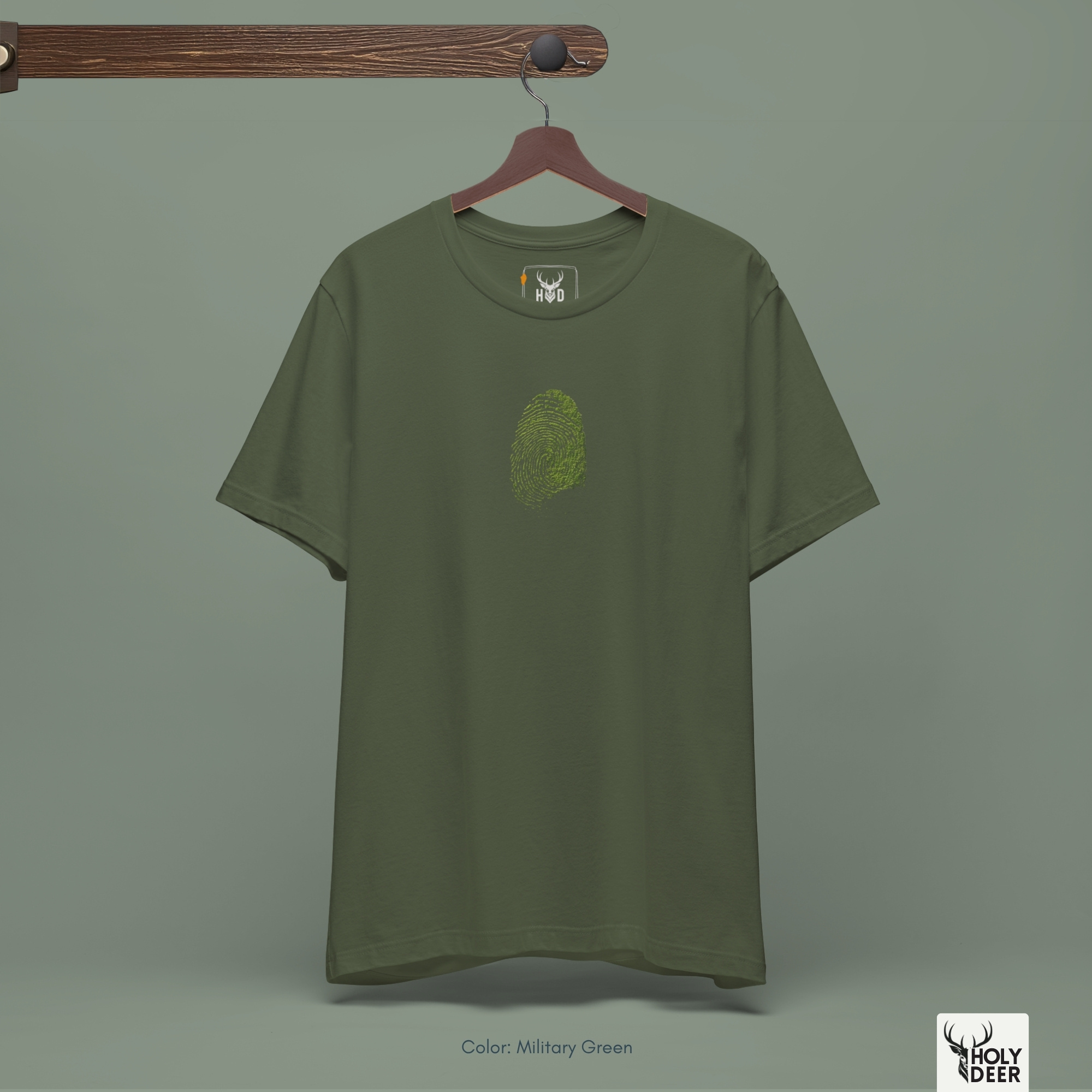 A detailed macro inspection of the Holydeer Clothing Green Identity Tee focusing entirely on the realistic environmental center print texture. This specific section tracks the delicate desaturated green paint strokes, organic symmetry loops, shadow depths around the finger edges, and dense ink layering forming the core of the eco activist cloth symbol.