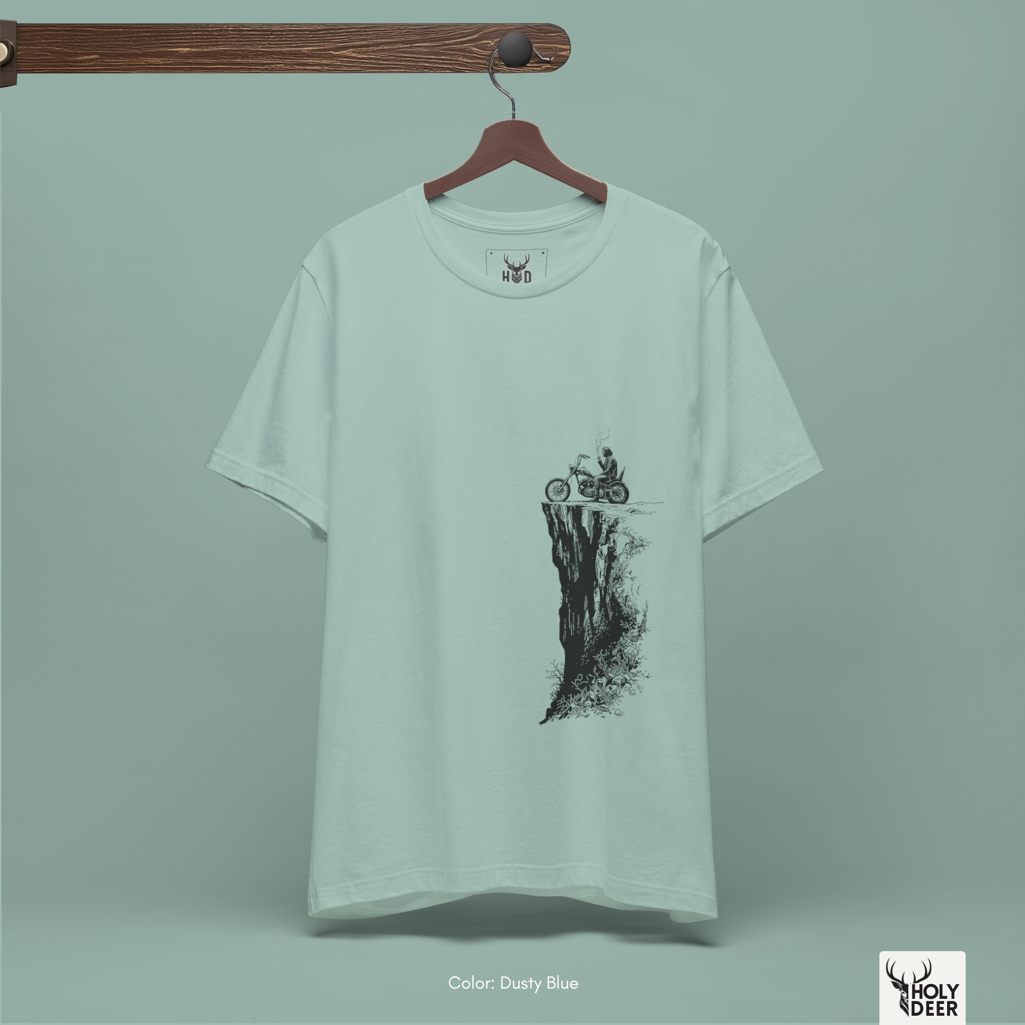 A detailed macro inspection of the Holydeer Clothing Biker Graphic Tee focusing entirely on the vertical rocky cliff face graphic. This specific section tracks the dense black screen ink layers, sketchy distressed rock textures, miniature mountain shrub lines, and sharp outer boundary tracks forming the core of the cliff adventure tee symbol.