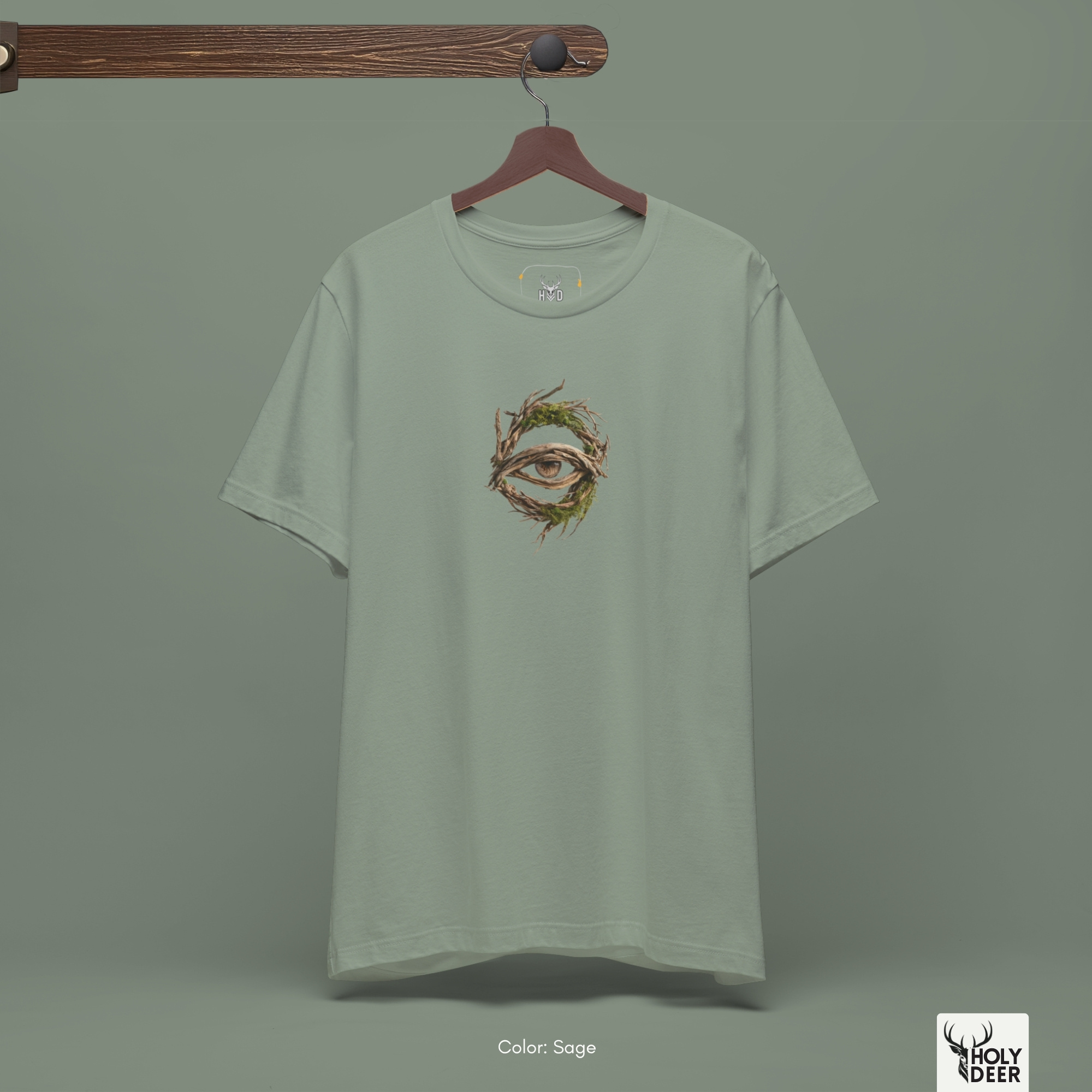 A commercial catalog layout tracking the Holydeer Clothing Forest Eye Shirt hanging cleanly from a custom timber stand. The product framework documents accurate mystic roots tee material behavior, soft chest wrinkles, and balanced square casual fit parameters for high-end boutique distribution.