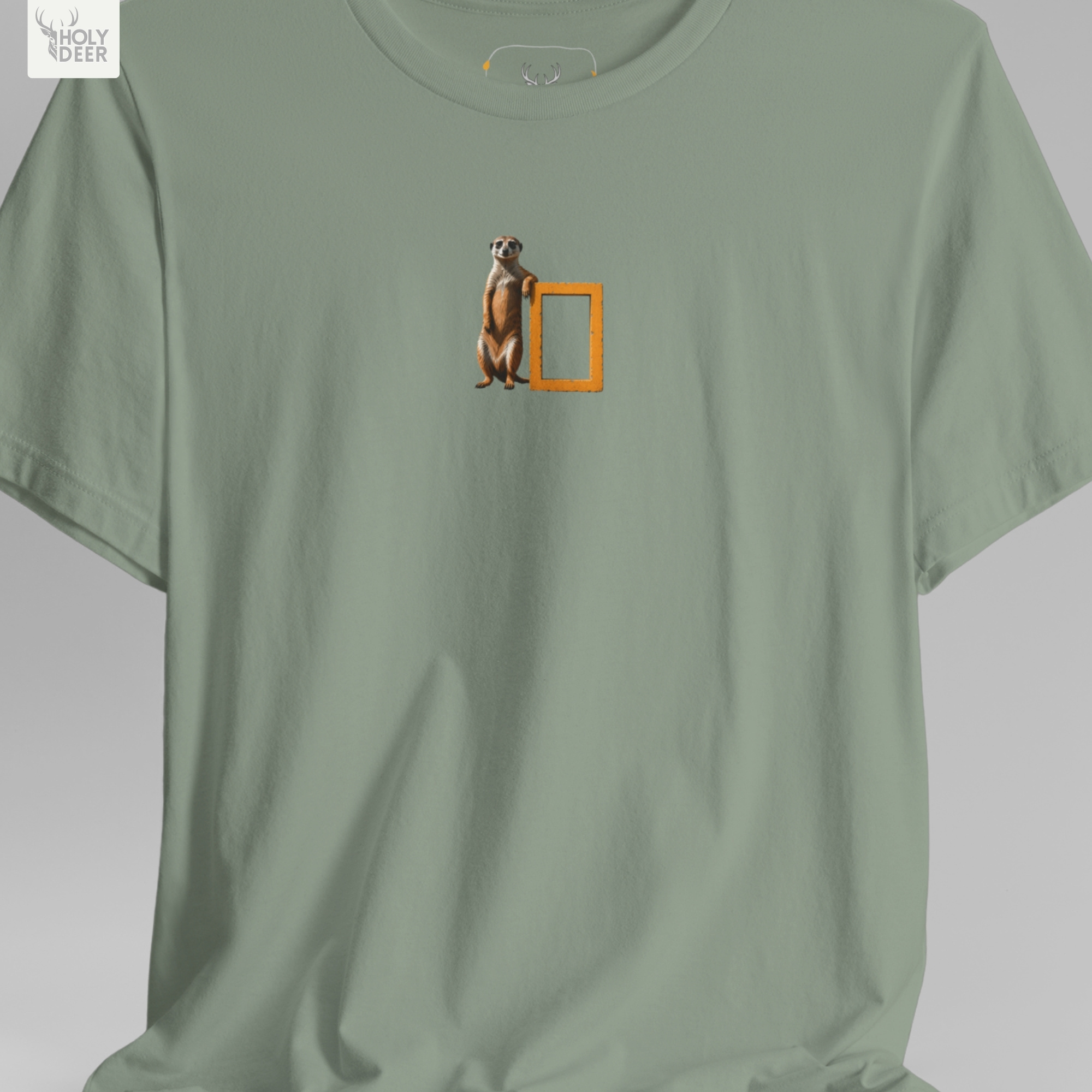 A commercial catalog layout tracking the Holydeer Clothing Meerkat Graphic Tee hanging cleanly from a custom timber stand. The product framework documents accurate funny nature top material behavior, soft chest wrinkles, and balanced square casual fit parameters for high-end boutique distribution.