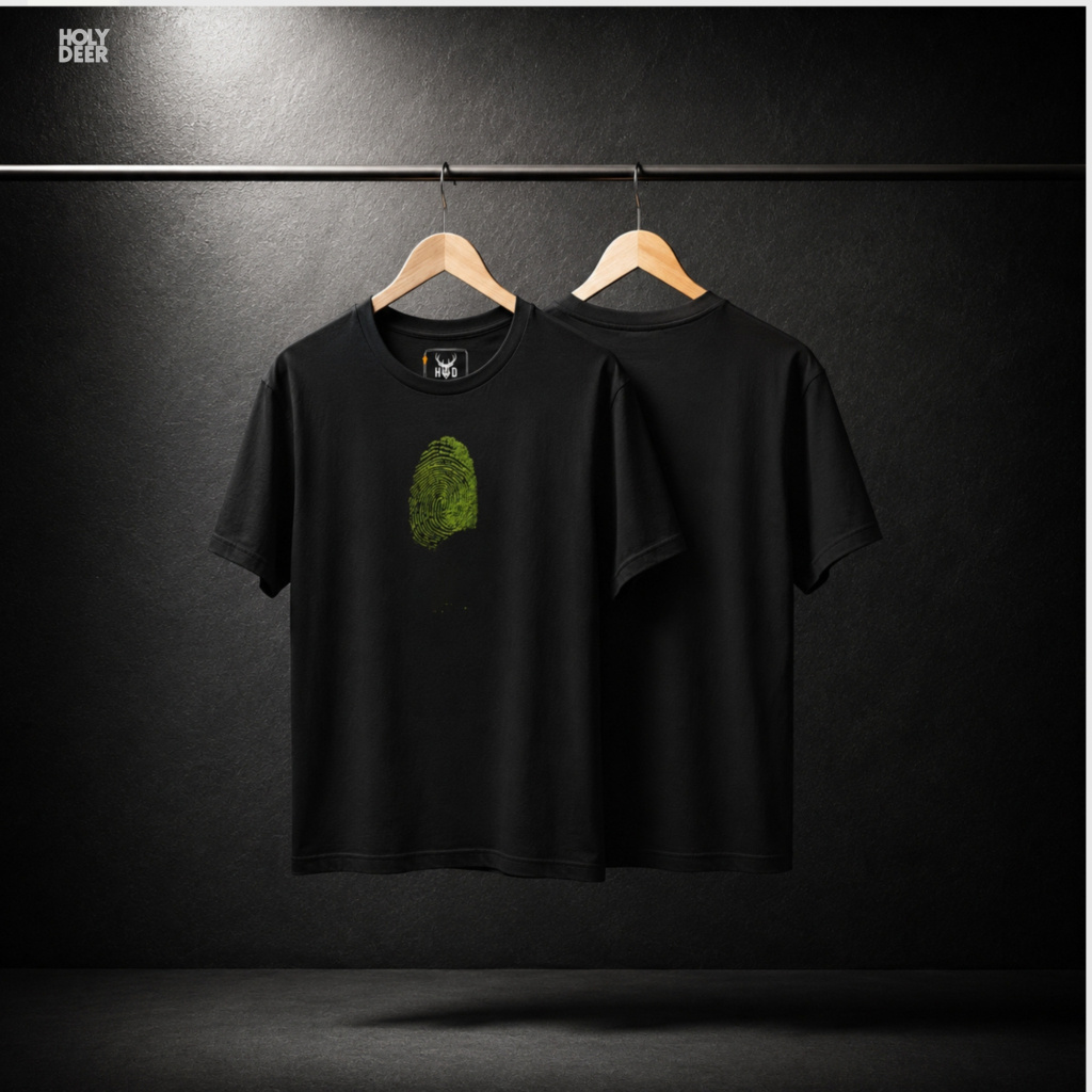 An overhead creative flat lay arrangement displaying the Holydeer Tee Green Identity Tee folded neatly next to raw styling elements. The merchandise is grouped zekice with deep black shungite mineral stones, actual preserved green moss patches, raw hemp coordinates, and alternative fingerprint leaf top lookbook magazines.