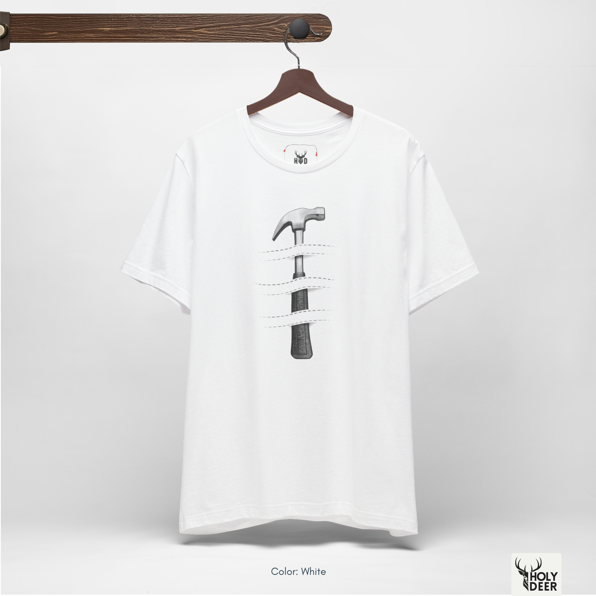 An overhead creative flat lay arrangement displaying the Holydeer Tee Hammer Graphic Tee folded neatly next to raw styling elements. The merchandise is grouped zekice with deep black shungite mineral stones, raw steel mechanical parts, an antique iron compass tool, and alternative hardware tshirt lookbook magazines.